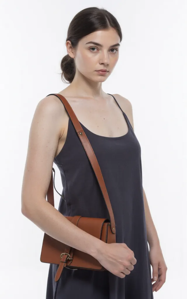 A French female model with a Shoulder bag, wearing a dress, against a white background, in a front   facing close   up